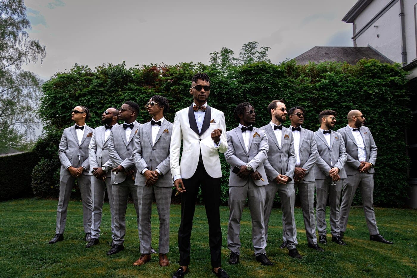A sharply dressed group of friends in suits and tuxedos celebrating together at a bachelor party